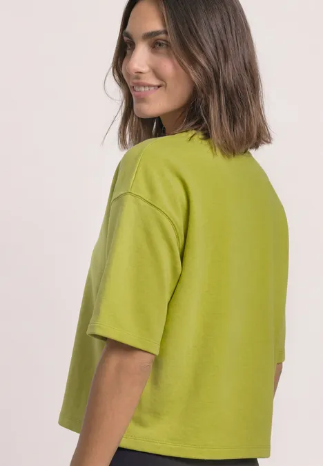 Sweatshirt met korte mouwen en ronde hals apple lime Frau mit halblangen braunen Haaren blickt lächelnd über die Schulter auf ein limettengrünes, kastiges T-Shirt.