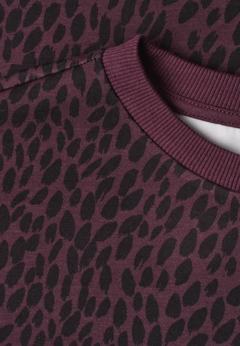 Bluza z krótkim rękawem i okrągłym dekoltem rustic rouge Zbliżenie bordowego swetra z ciemnym, organicznym wzorem plam.