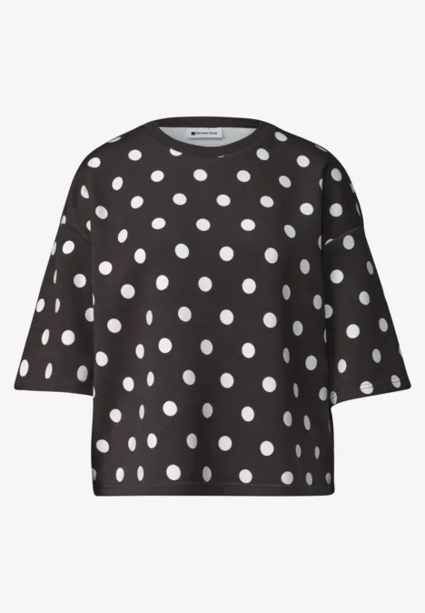Schwarzes kurzärmeliges Oberteil mit weißen Polka-Dots.