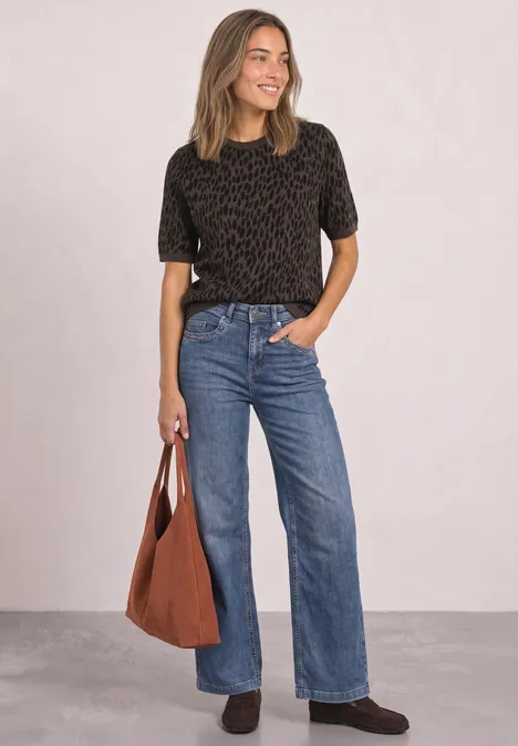 Jacquardtrui met ronde hals en luipaardprint molten earth Vrouw met zwart shirt, wijde jeans en bruine tas, glimlachend voor een neutrale achtergrond.