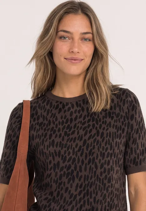 Jacquardtrui met ronde hals en luipaardprint molten earth Een vrouw met lang haar draagt een kort mouw T-shirt in bruin-zwarte print en een schoudertas.