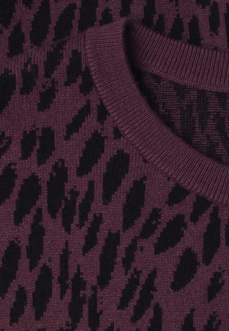 Nahaufnahme des Rundhalsausschnitts eines Strickpullovers mit lila-schwarzem Tiermuster.
