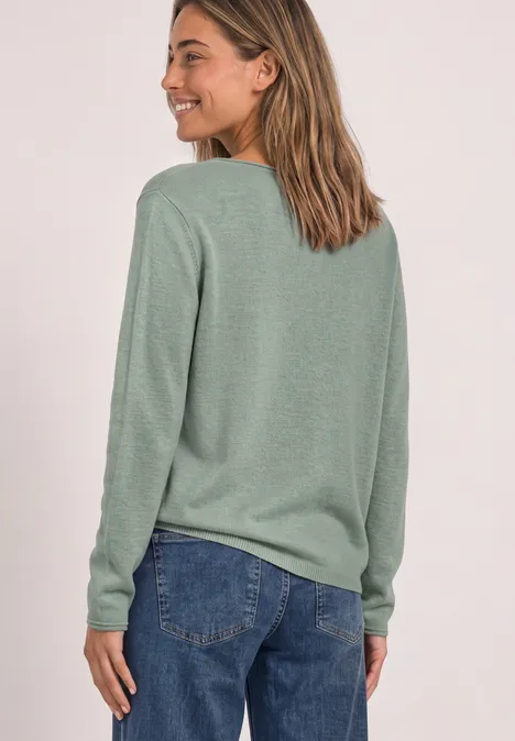 Vue de dos d’une femme en pull vert et jean.