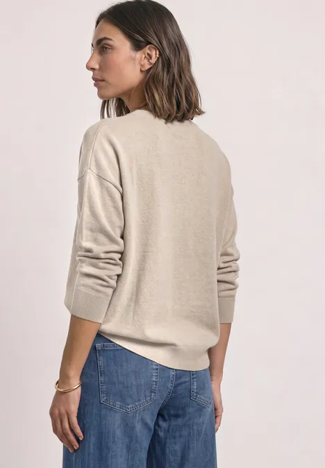 Pullover mit Boat Neck und Rollkanten clay sand mel. Frau von hinten in beigem Pullover und blauen Jeans vor hellem Hintergrund.