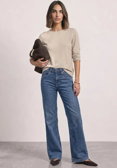 Pullover mit Boat Neck und Rollkanten clay sand mel. Frau in beigem Pullover und blauen Jeans, hält eine Tasche in der Hand.