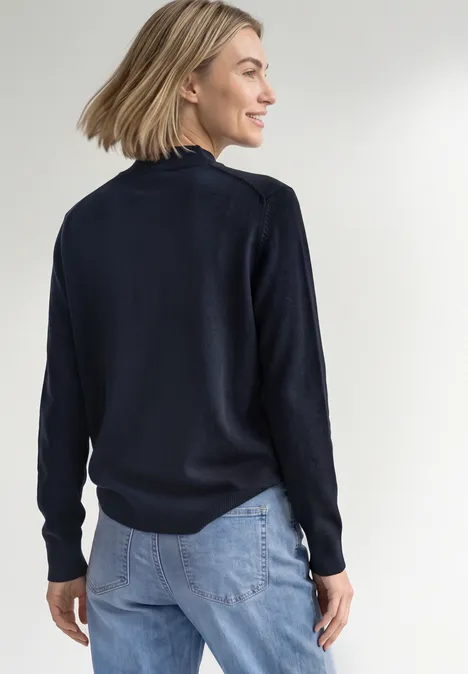 Basic Pullover mit Turtle Neck darkest blue Eine Frau von hinten in dunkelblauem Pullover und hellblauer Jeans, Blick seitlich, lächelnd.
