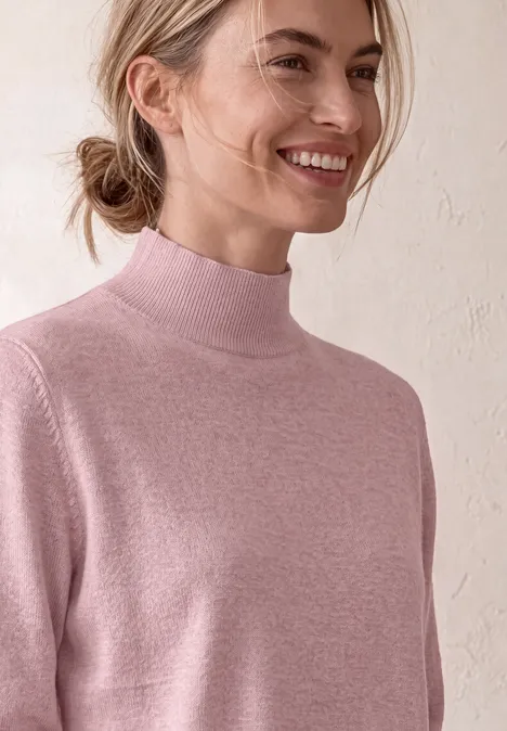 Basic Pullover mit Turtle Neck quiet rose mel. Junge Frau mit zurückgebundenem Haar und rosa Rollkragenpullover lächelt vor hellem Hintergrund.