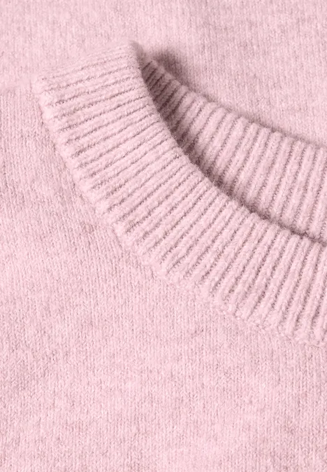 Nahaufnahme eines flauschigen, rosa Pullovers mit geripptem Kragen.