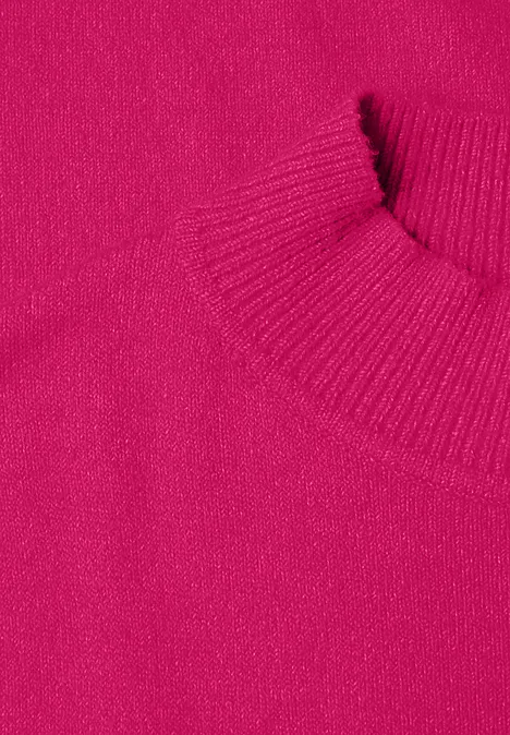 Nahaufnahme eines pinkfarbenen Strickpullovers mit geripptem Kragen und Ärmelbündchen.