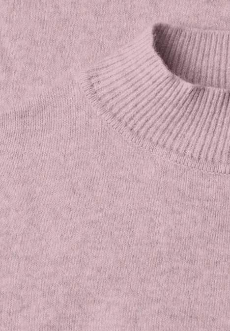 Nahaufnahme eines altrosa Strickpullovers mit geripptem Kragen.