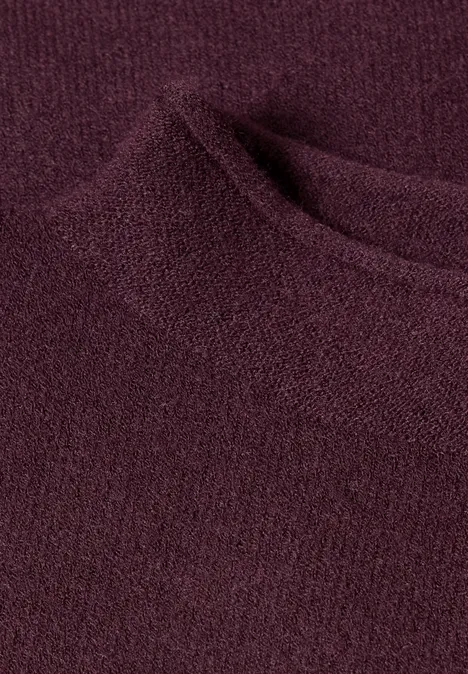 Nahaufnahme eines weichen, dunkelroten Strickstoffs mit rundem Ausschnitt.