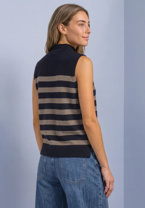 Rückansicht einer Frau, die eine ärmellose, gestreifte Strickweste mit Stehkragen und Jeans trägt.