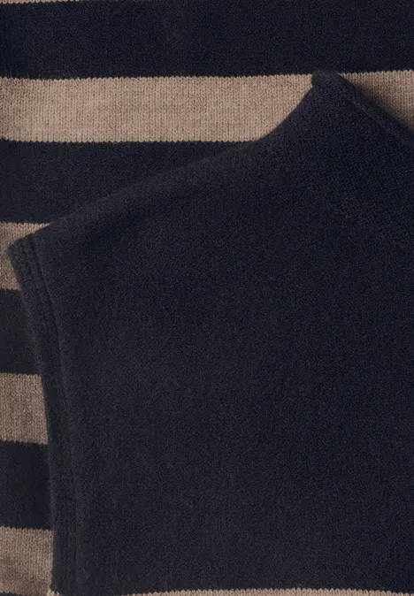 Schwarzes ärmelloses Stricktop liegt auf einem gestreiften Pullover in Beige und Schwarz.
