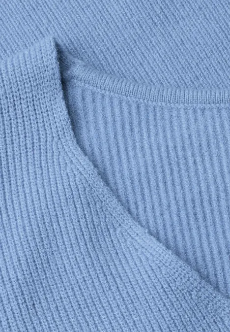 Nahaufnahme eines hellblauen, gerippten Strickpullovers mit V-Ausschnitt.