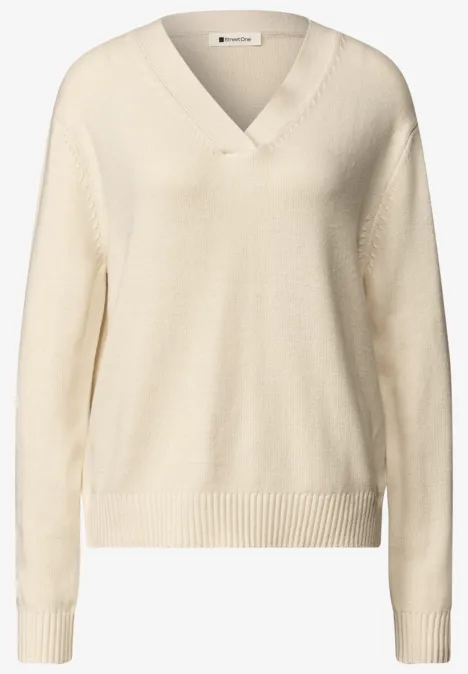 Pull en maille beige à col V, manches longues et bords côtelés.