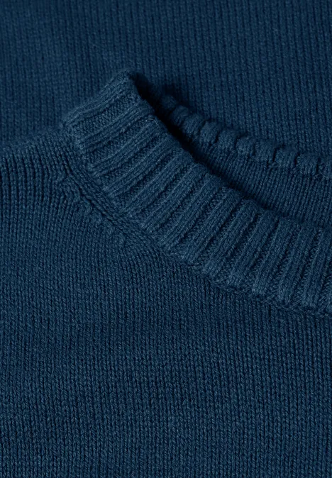 Close-up van een donkerblauwe, fijngebreide trui met ronde hals.