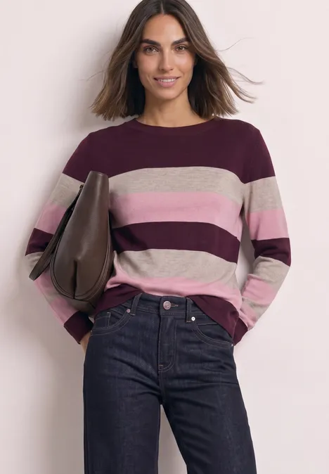 Pullover mit Rundhals und Streifen rustic rouge Eine Frau trägt einen gestreiften Pullover in Burgund-, Rosa- und Beigetönen und Jeans vor hellem Hintergrund.