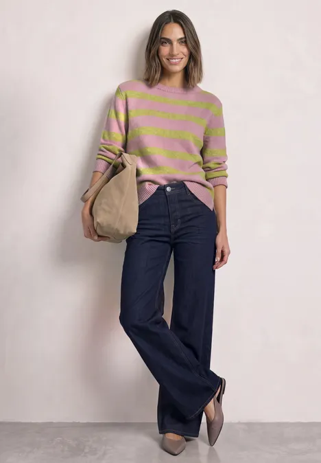 Pullover mit Boat Neck und Streifen apple lime Frau in rosa-grün gestreiftem Pullover, weiten Jeans und Beuteltasche vor hellem Hintergrund.