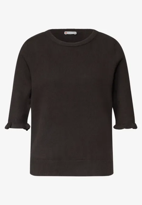 Schlichter schwarzer Kurzarm-Pullover mit Rüschenabschluss an den Ärmeln.
