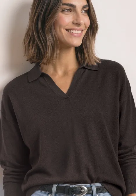 Frau im dunkelbraunen Pullover mit V-Kragen und Polokragen, lächelnd.