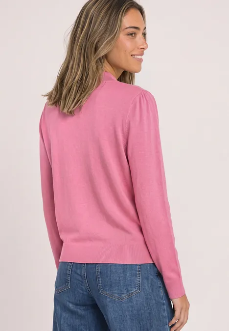 Frau im Profil mit rosa Pullover und blauer Jeans vor hellem Hintergrund.