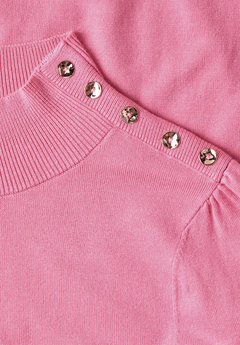 Rosa Strickpullover mit auffälligen goldfarbenen Knöpfen an der Schulterpartie.