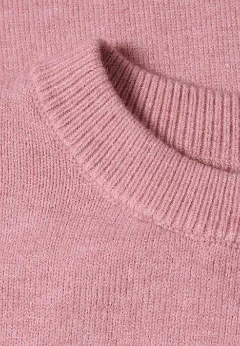Close-up van een roze fijngebreide trui met subtiele structuur.