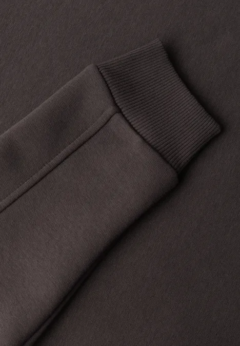 Nahaufnahme eines dunkelgrauen Sweatshirt-Ärmels mit geripptem Bündchen.
