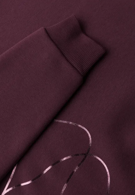 Nahaufnahme eines weinroten Sweatshirts mit glänzendem Linien-Print auf dem Ärmel.