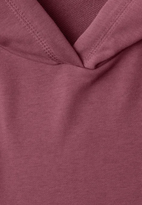 Nahaufnahme eines weinroten Kapuzenpullover-Stoffes mit sichtbarer Naht.