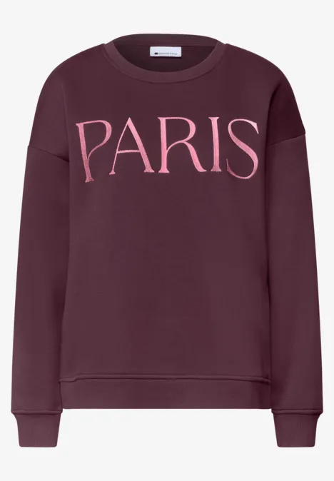 Dunkelrotes Sweatshirt mit rosa Schriftzug 'PARIS' auf der Brust.