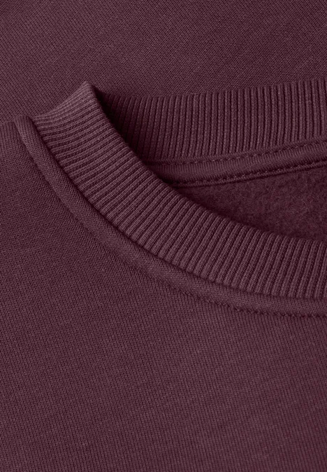 Nahaufnahme eines burgunderfarbenen Sweatshirts mit Rundhalsausschnitt und Rippbündchen.
