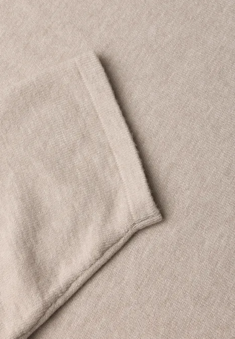 Close-up van een beige stof met een ingenaaide zak.