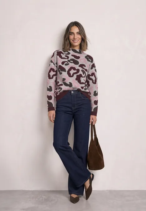 Femme en pull léopard, jean évasé bleu foncé, sac marron et chaussures pointues.