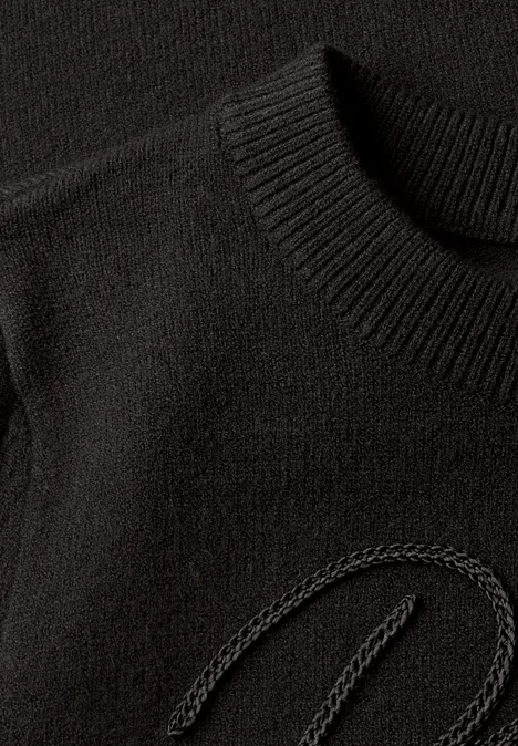 Nahaufnahme eines schwarzen Strickpullovers mit dezentem, eingearbeitetem Logo-Detail.