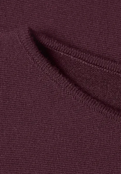 Dolman-trui met boothals rustic rouge Close-up van bordeauxrode gebreide stof met een klein zakje of gleuf.