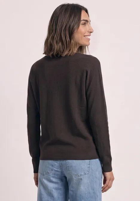 Sweter z rękawami typu dolman i dekoltem w kształcie łódki black coffee Kobieta od tyłu w brązowym swetrze i dżinsach.