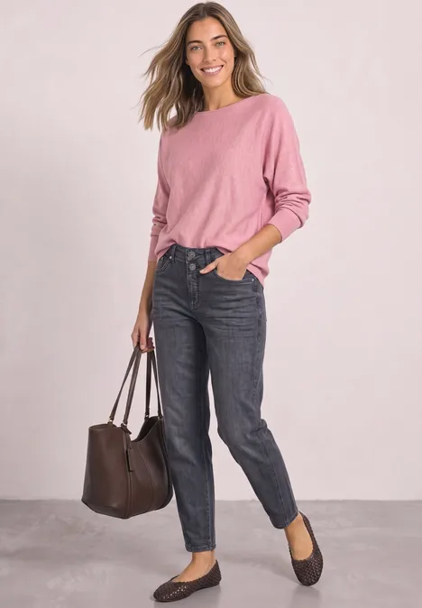 Sweter z rękawami typu dolman i dekoltem w łódkę vintage blush mel. Kobieta w różowym swetrze, ciemnych dżinsach, czarnych balerinach i brązowej torebce na jasnym tle.