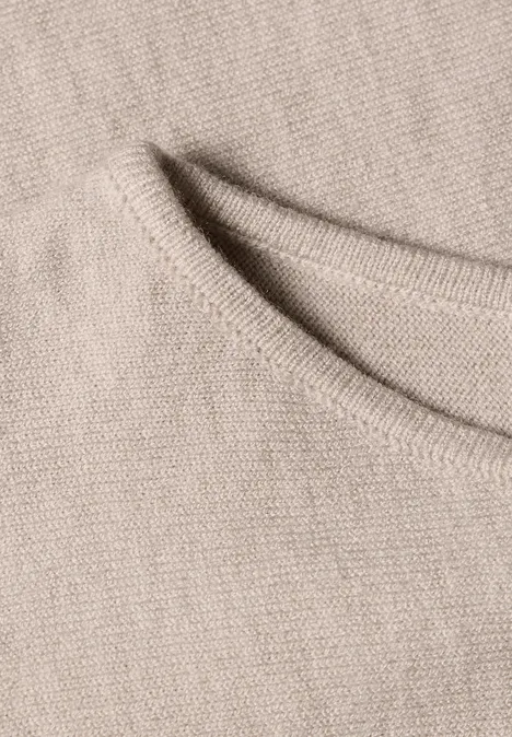 Sweter z rękawami typu dolman i dekoltem w kształcie łódki clay sand mel. Zbliżenie beżowego dzianinowego materiału z przeszyciem brzegowym.