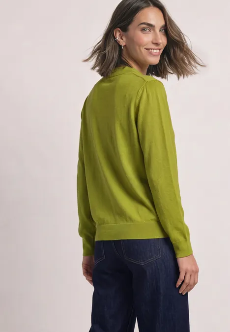 Pullover in Unifarbe mit Rundhals apple lime Eine Frau in grüner Strickjacke und Jeans schaut lächelnd über die Schulter.