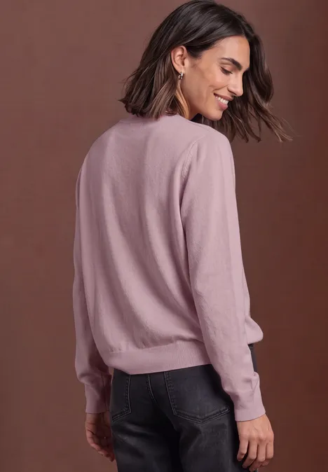 Pullover in Unifarbe mit Rundhals quiet rose Frau in rosa Pullover und dunkler Jeans von hinten, dreht den Kopf und lächelt.