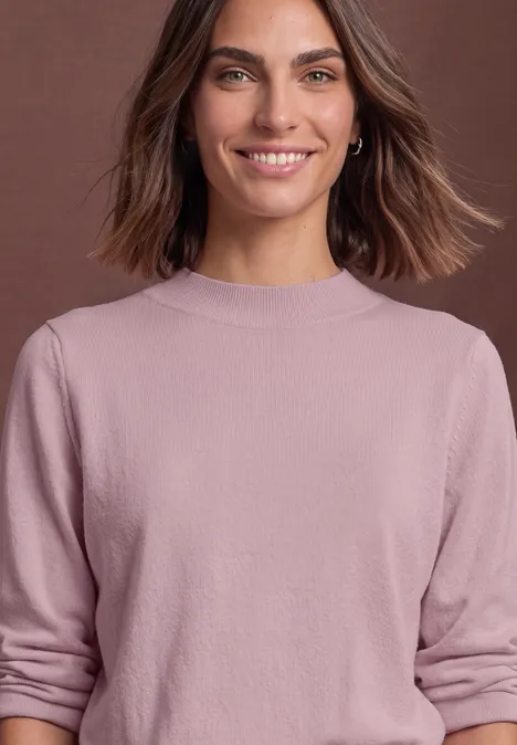 Pullover in Unifarbe mit Rundhals quiet rose Lächelnde Frau mit braunen Haaren und rosa Pullover vor neutralem Hintergrund.