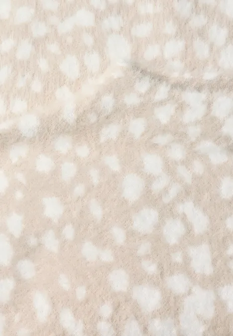 Naheinstellung einer flauschigen, beigefarbenen Oberfläche mit weißen Punkten.