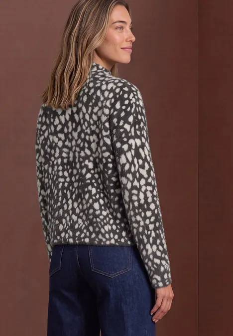 Frau in gemusterter schwarz-weißer Jacke und Jeans, von hinten fotografiert.