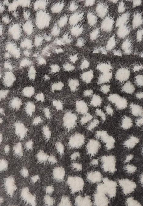 Flauschiges Fell mit unregelmäßigen weißen Tupfen auf grauem Hintergrund