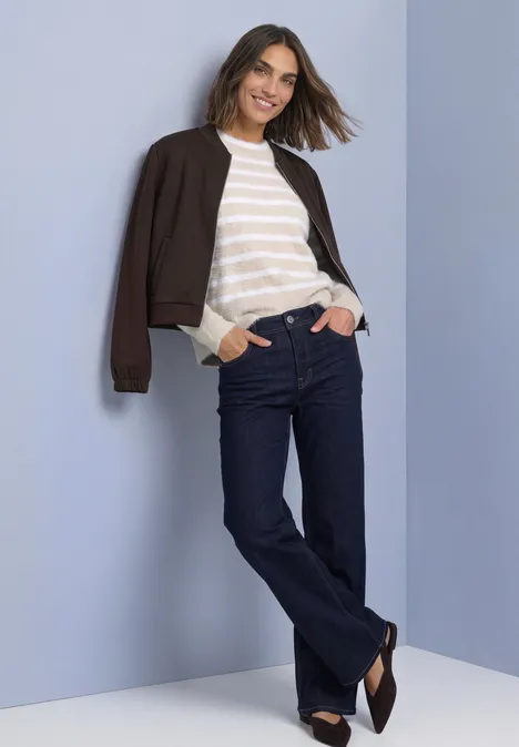 Langarm Pullover mit Rundhals und Streifen clay sand Eine lächelnde Frau lehnt entspannt an einer Wand, trägt Jeans, gestreiftes Shirt und dunkle Jacke.