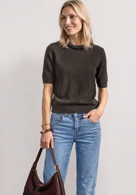 Kurzarm Pullover mit Schmuckdetail black coffee mel. Lächelnde Frau in dunklem Kurzarmpullover, blauen Jeans und brauner Ledertasche.