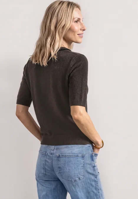 Kurzarm Pullover mit Schmuckdetail black coffee mel. Eine Frau in schlichter, dunkelbrauner Strickbluse mit halblangen Ärmeln und blauen Jeans vor hellem Hintergrund.