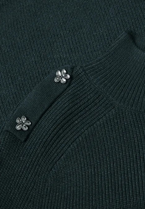 Nahaufnahme eines dunkelgrünen Strickoberteils mit zwei silbernen Blumenknöpfen
