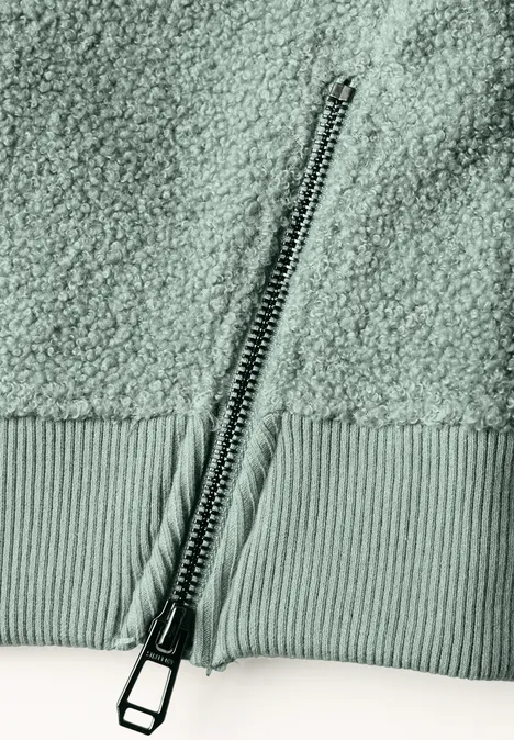 Nahaufnahme eines Reißverschlusses an einem weichen, strukturierten Teddy-Fleece-Stoff.